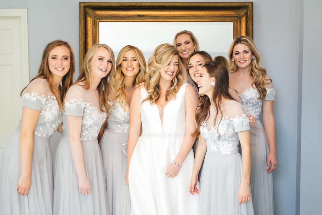 Bridesmaids laughing together while getting dressed 