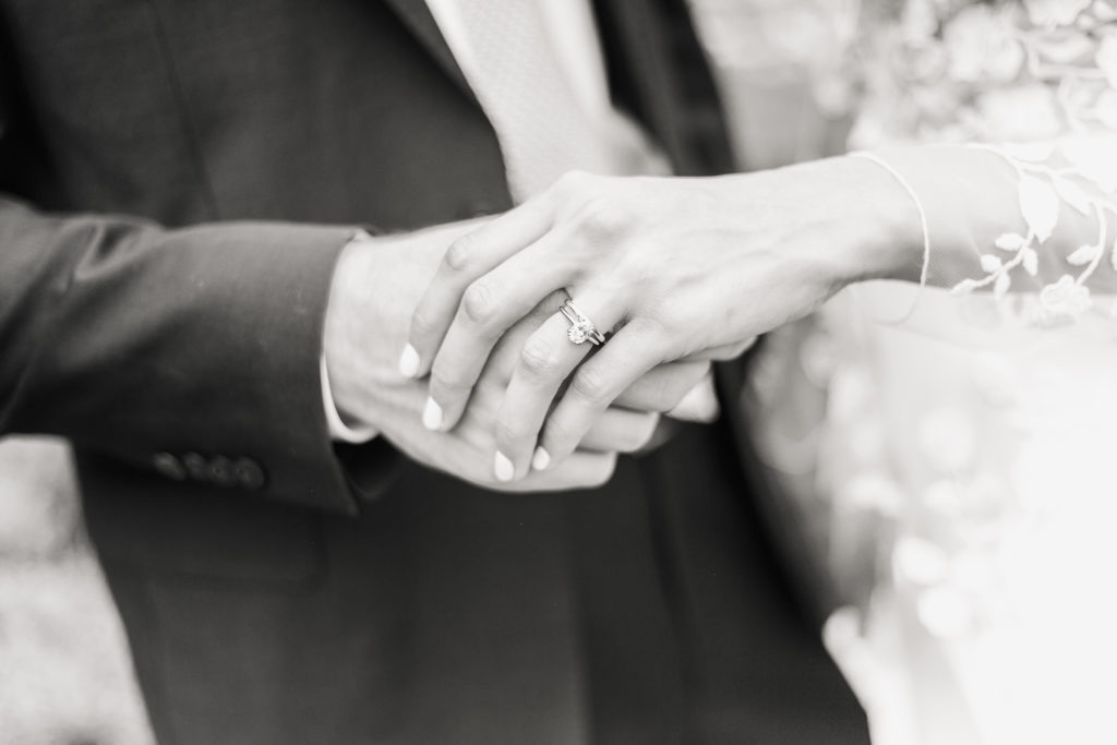 Black and white image of a bride and groom holding hands