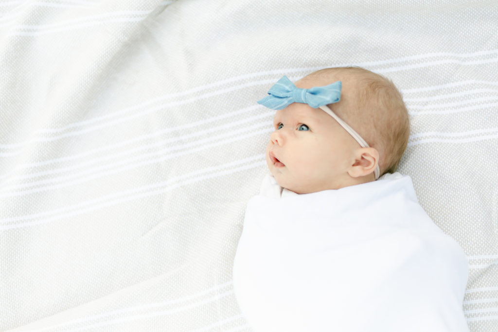A newborn baby laying on a striped blanket during a Rochester NY newborn photography session.
