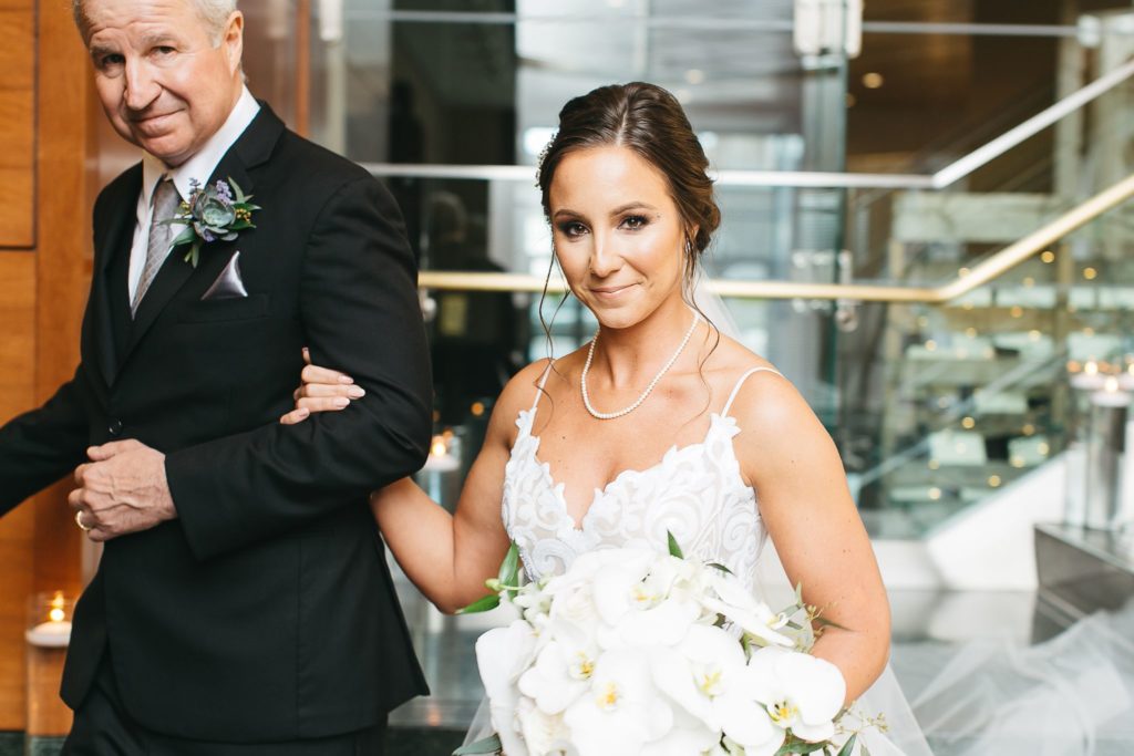 A bride smiling at the camera before walking down the aisle at the Wintergarden wedding.