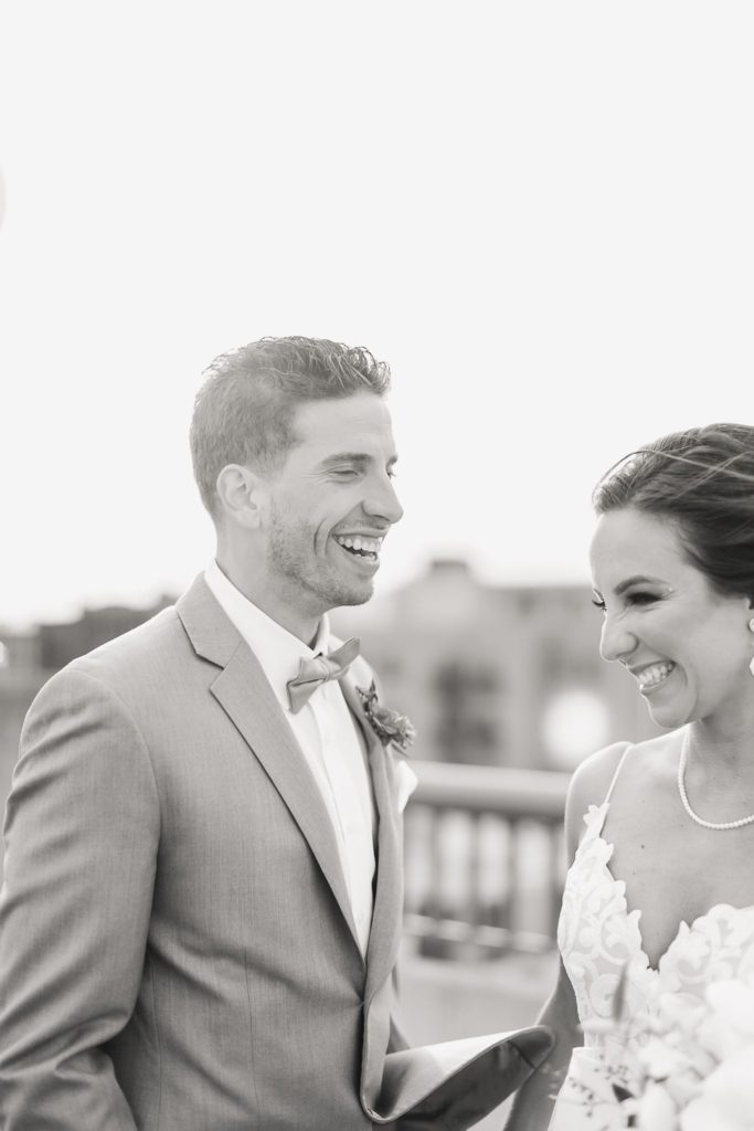 A wedding couple laughing on a rooftop at sunset.