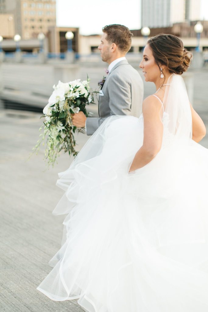 A bride and groom walking across a downtown rooftop.