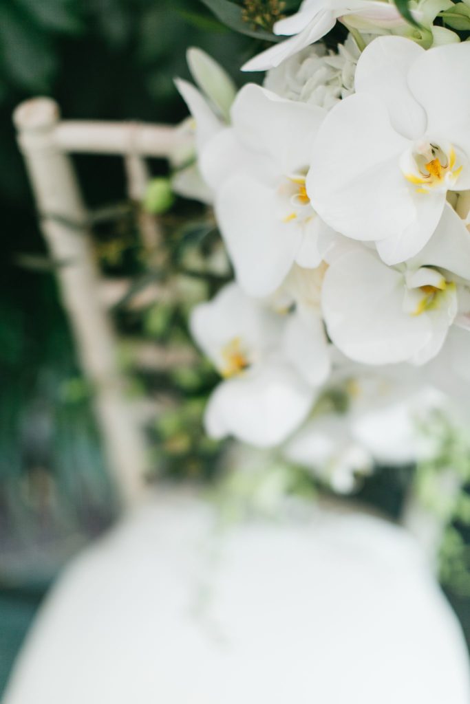 A luxurious orchid bridal bouquet on a white chivari chair.
