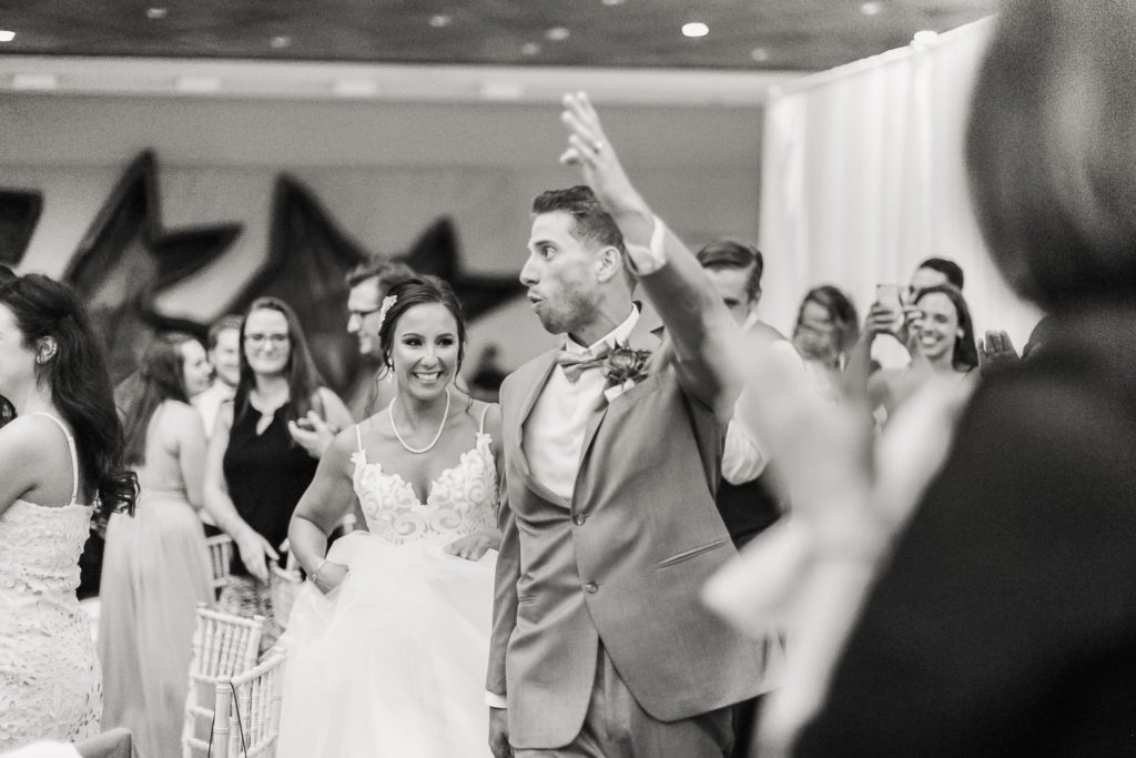 A bride and groom celebrating and waving to guests after a Wintergarden wedding ceremony.