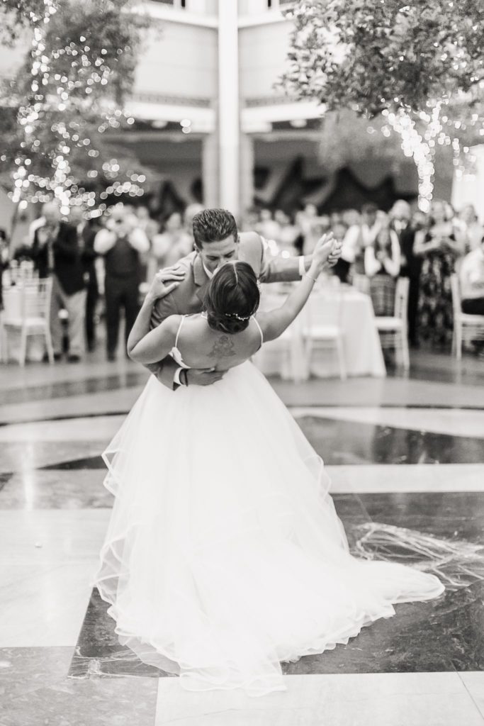 A black and white image of a groom dipping his bride on the dance floor at Rochester NY's Wintergarden.