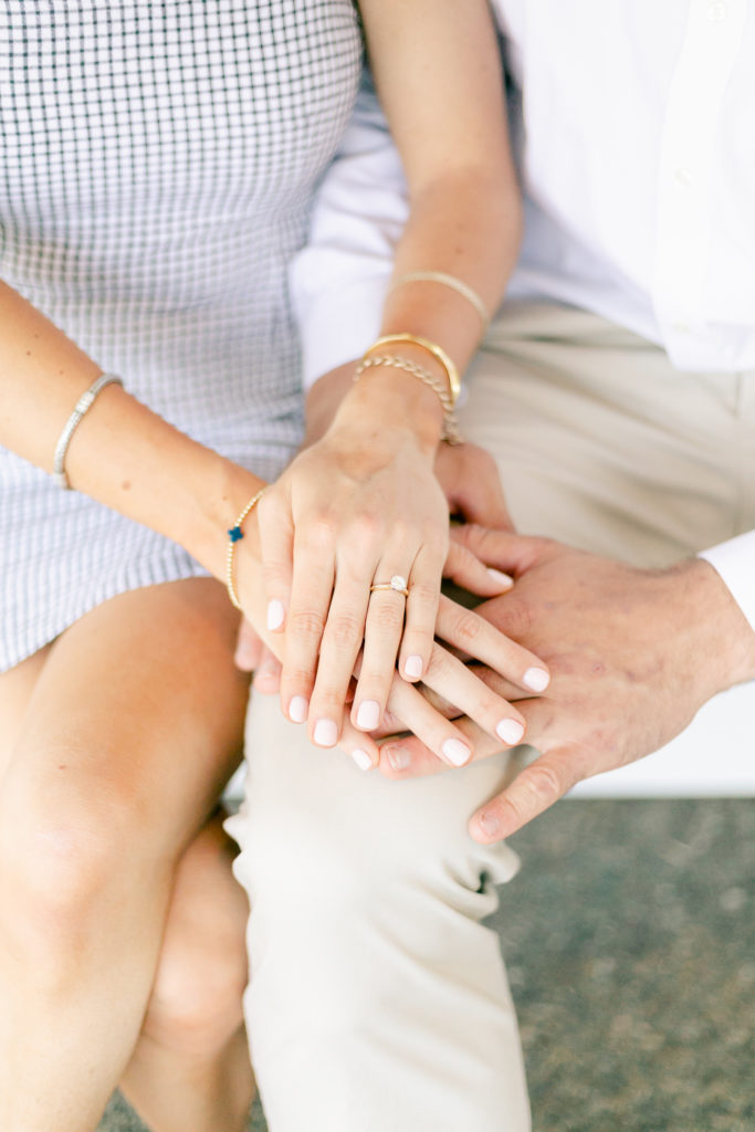 An engaged couple holding hands, displaying their engagement ring.