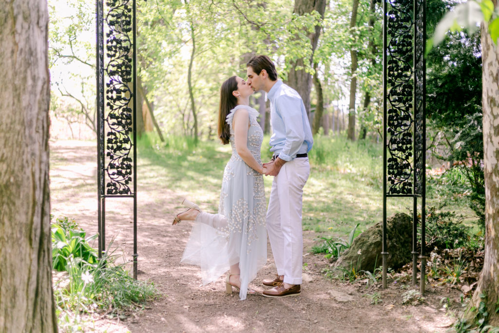 A couple kissing under the Poet's Garden archway at a Highland Park engagement session.