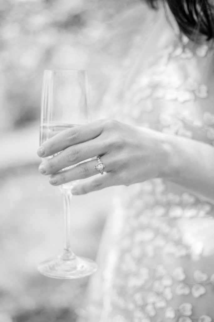 A bride holding a glass of champagne and showing her engagement ring.