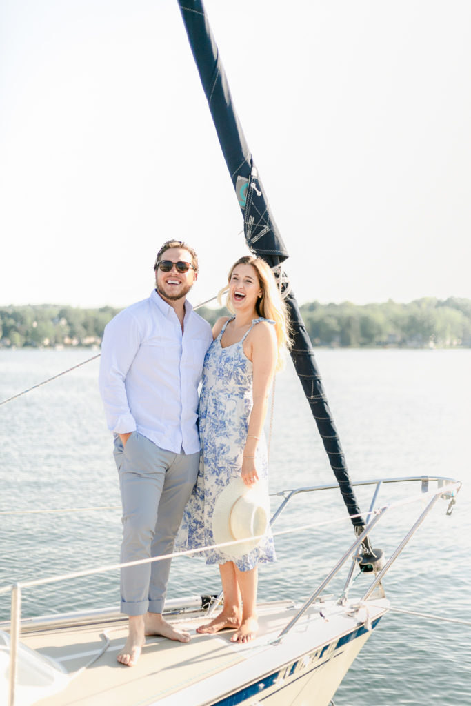 An engaged couple laughing on a sailboat during their engagement session.