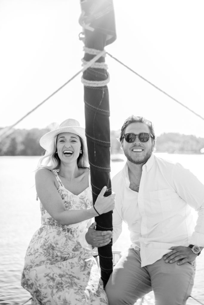 A black and white image of an engaged couple sailing on a sailboat.