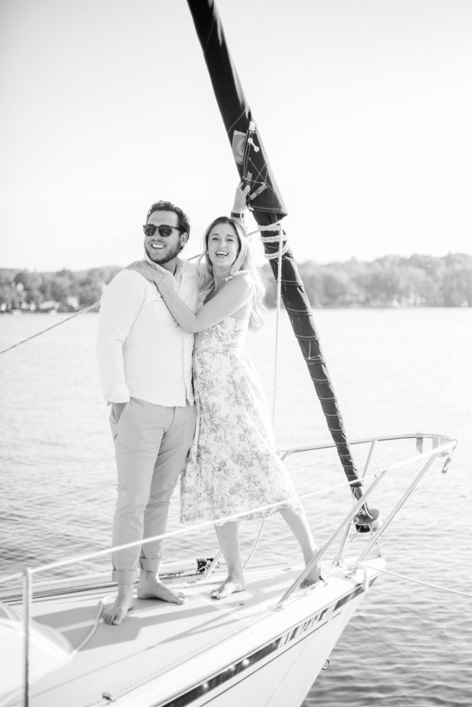 Black and white image of an engaged couple on a sailboat.